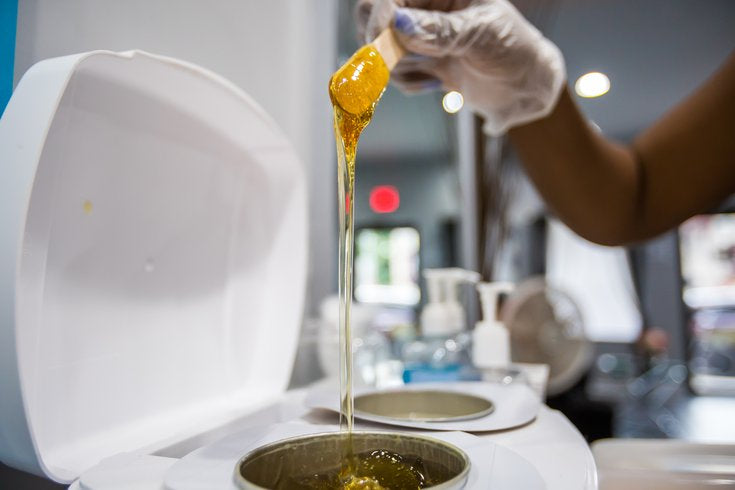 Honey wax drips from an applicator at the Triple S Hair Lounge in West Philadelphia.