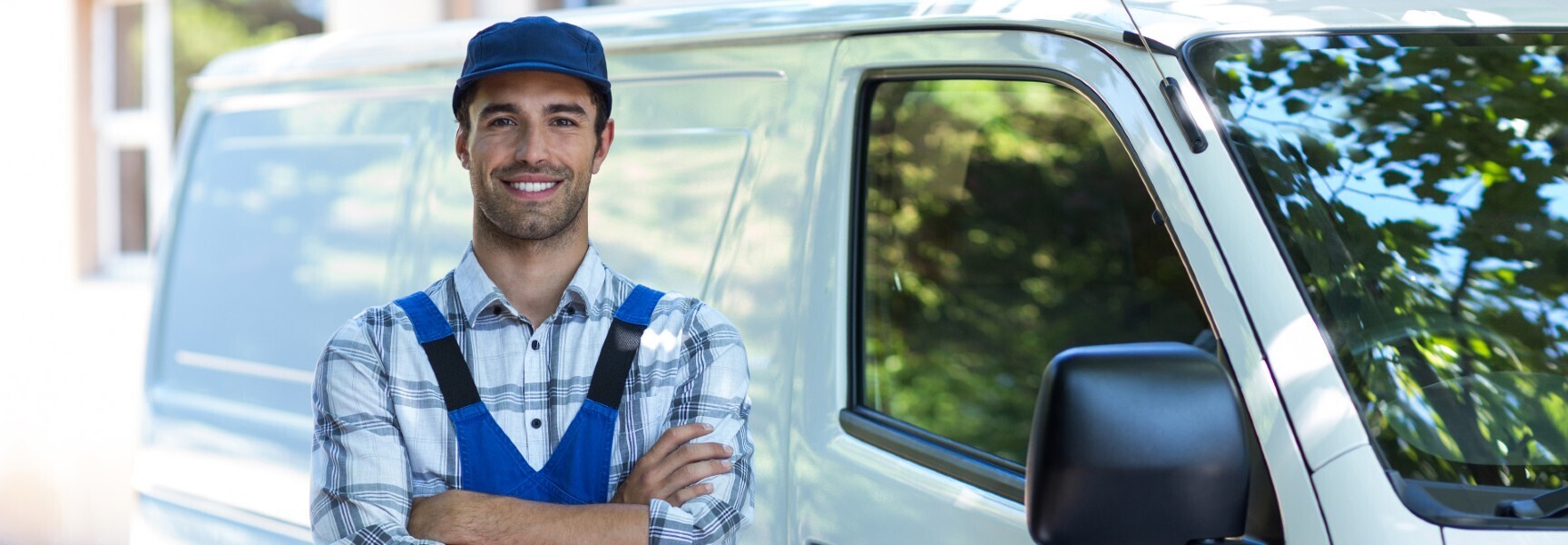 A white van parked on a street, with a person standing next to it, ready to load or unload items.