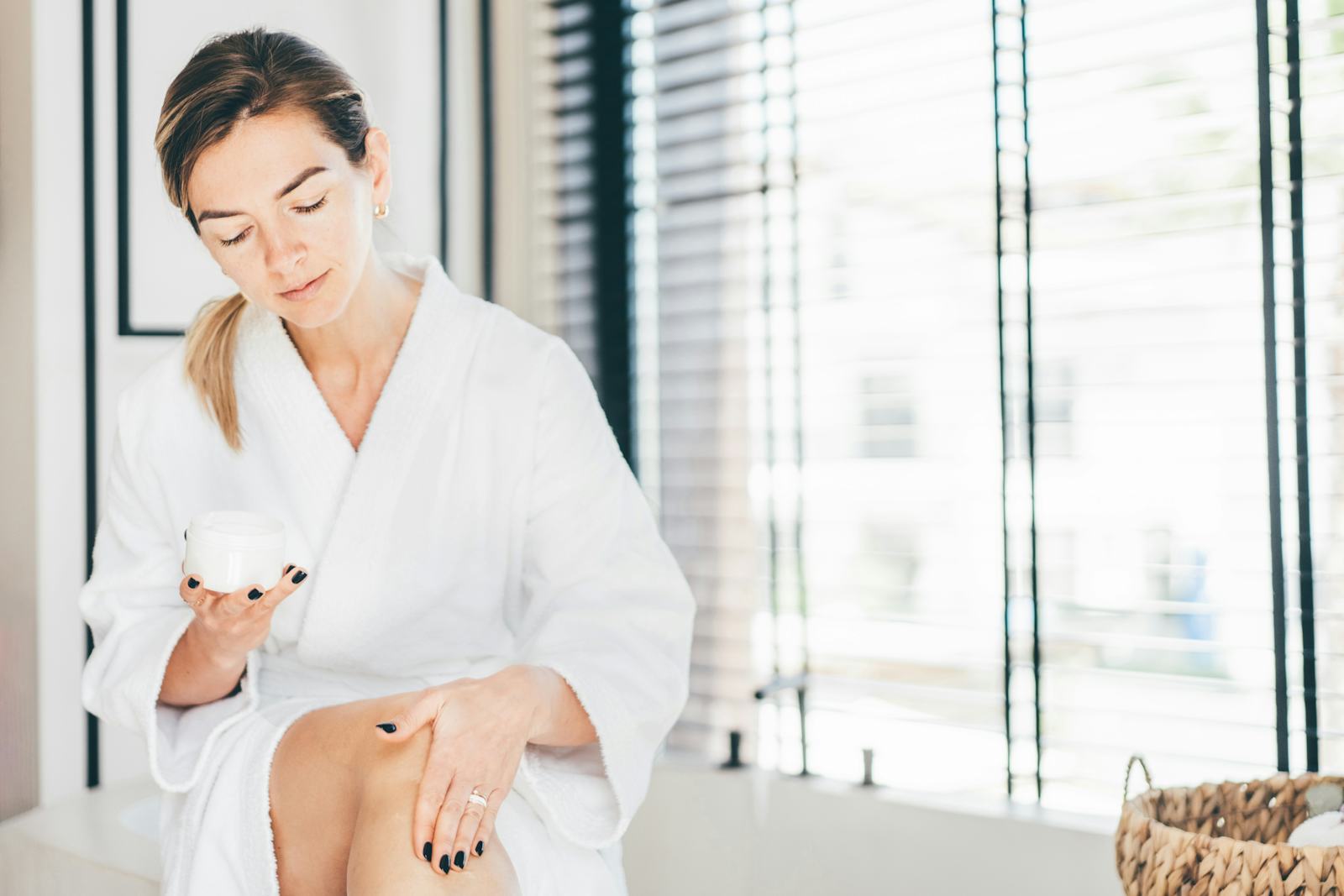 Woman takes care of her skin. Woman applies cream to her legs in the bathroom.