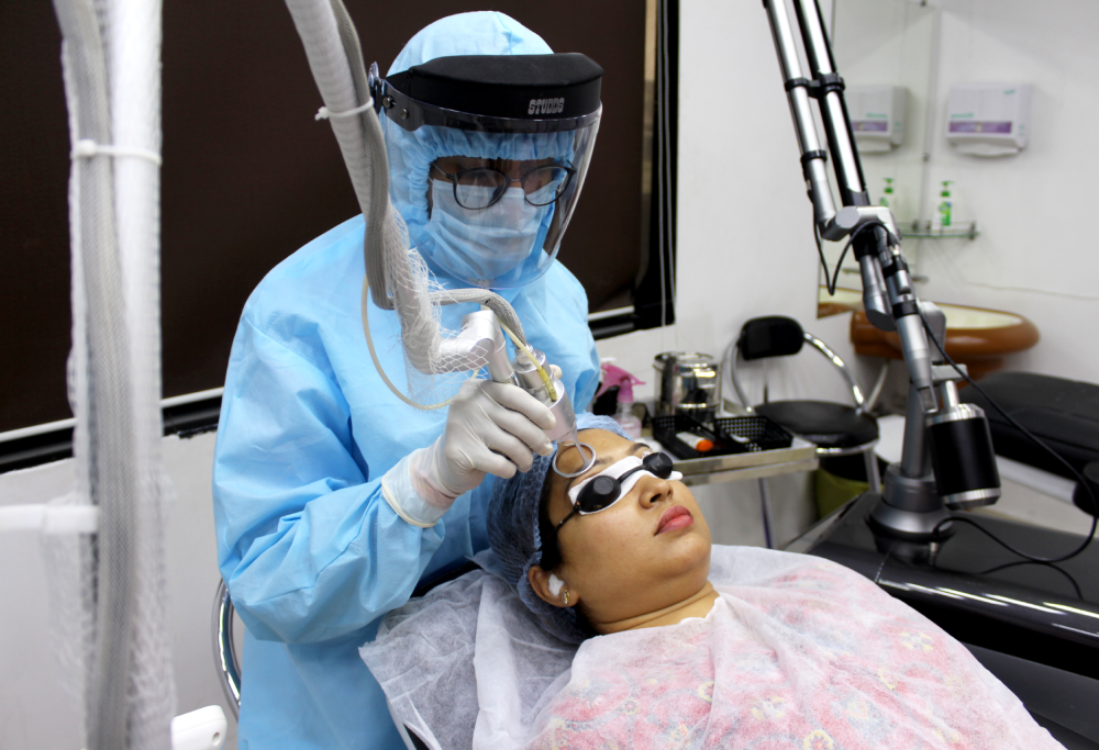 A laser technician performing laser treatment on a patient