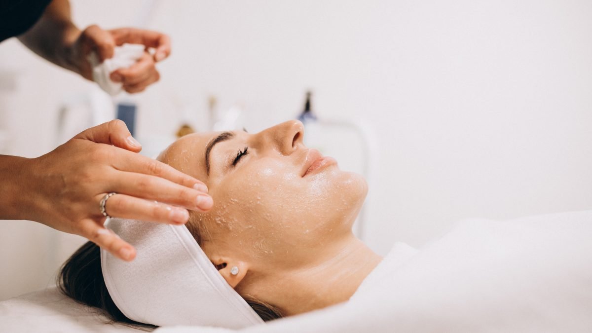 Cosmetologist cleaning face of a woman in a beauty salon