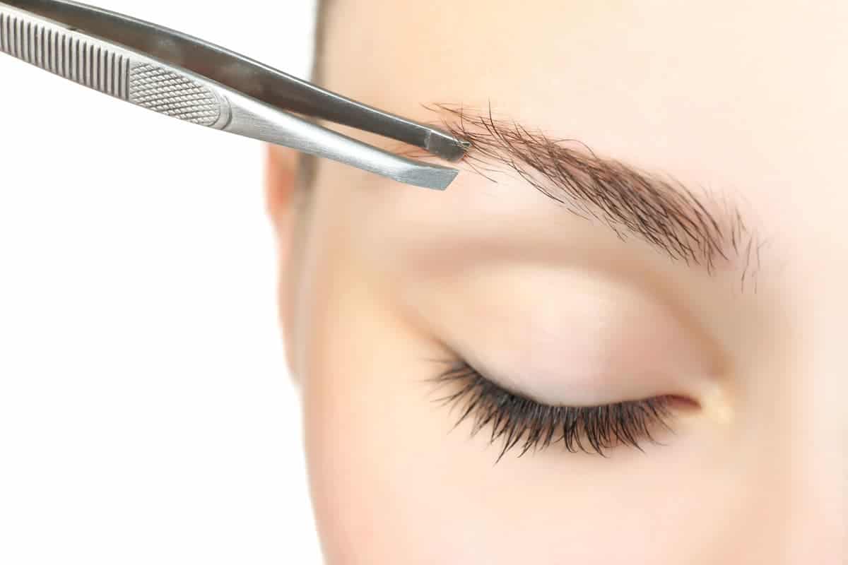 woman closing her eyelid while plucking eyebrows