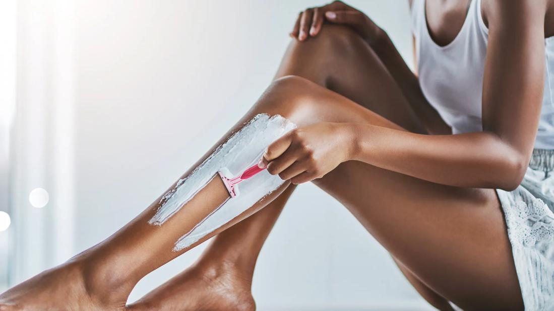 Person sitting, shaving their leg with shaving cream