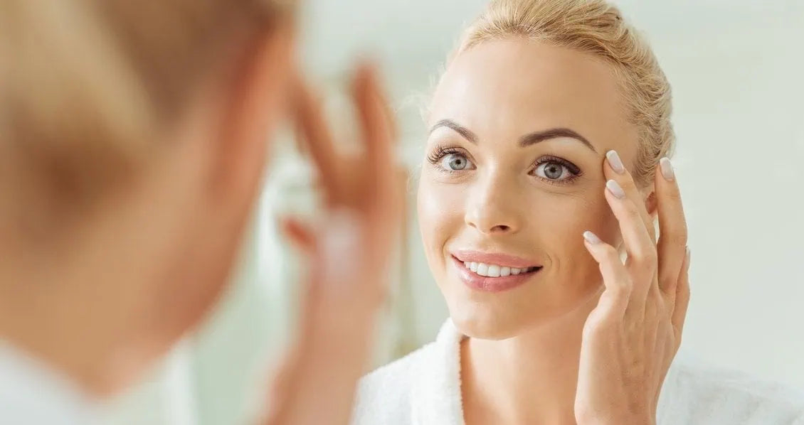 A woman looks at her face in the mirror.